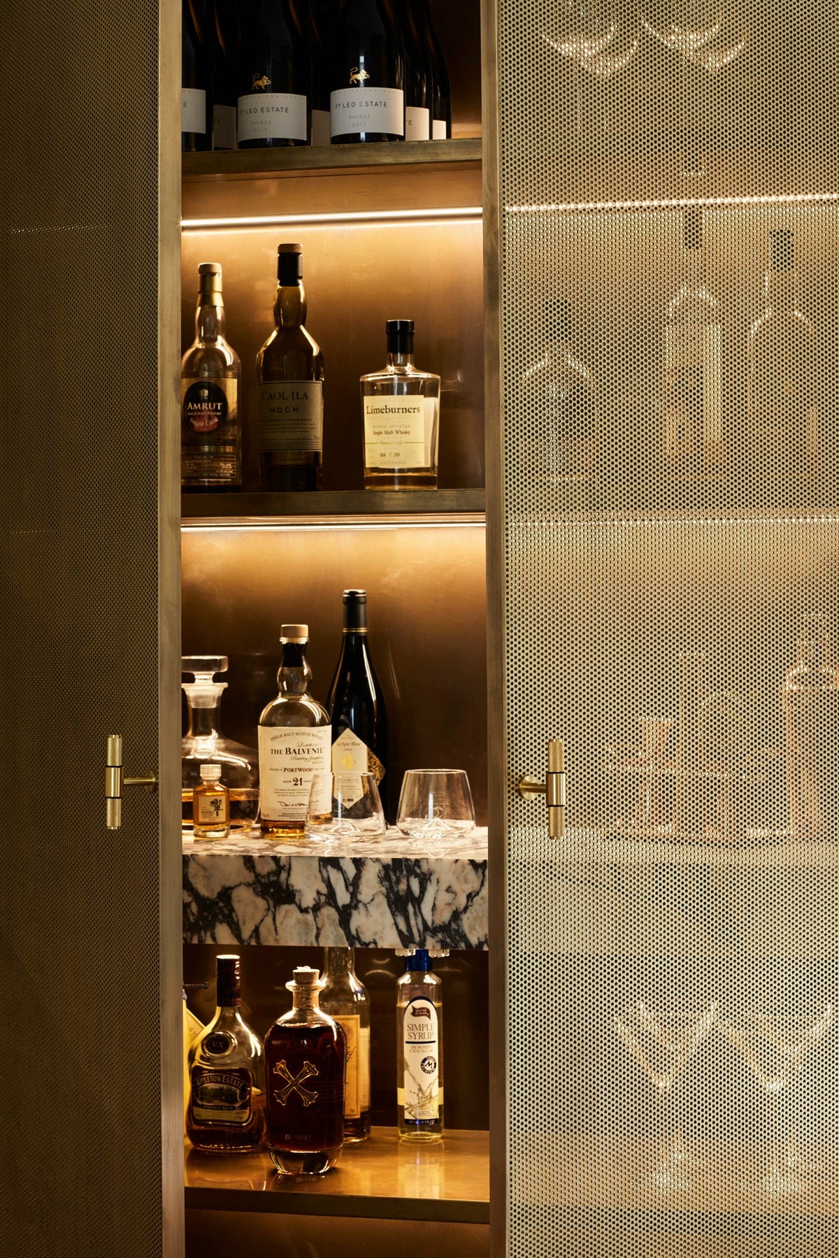 a gold cocktail cabinet with the door open, showing bottles of liquor inside