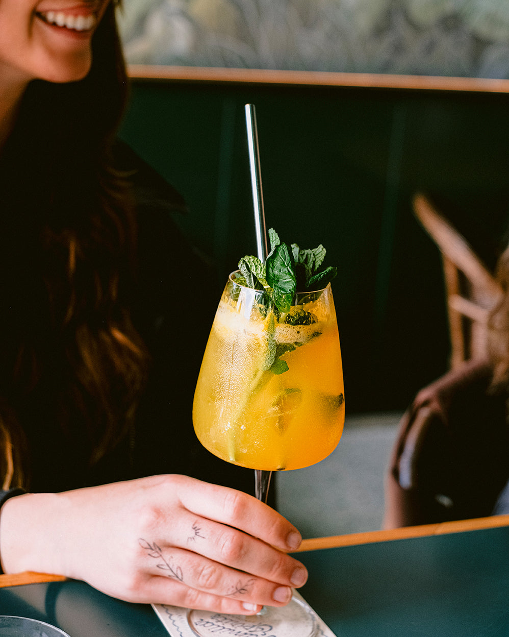 a hand holding an orange cocktail